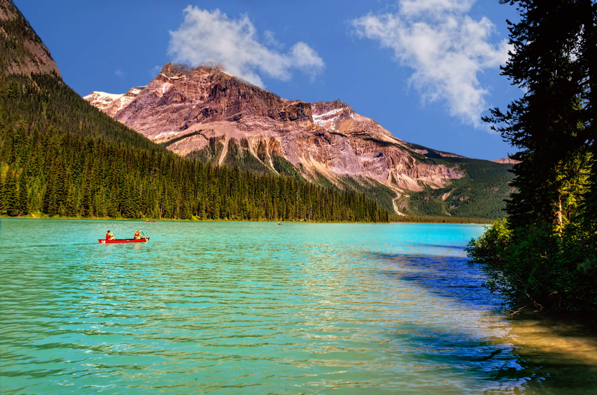 emerald green lake, surrounded by coniferous forests and rocky m ...